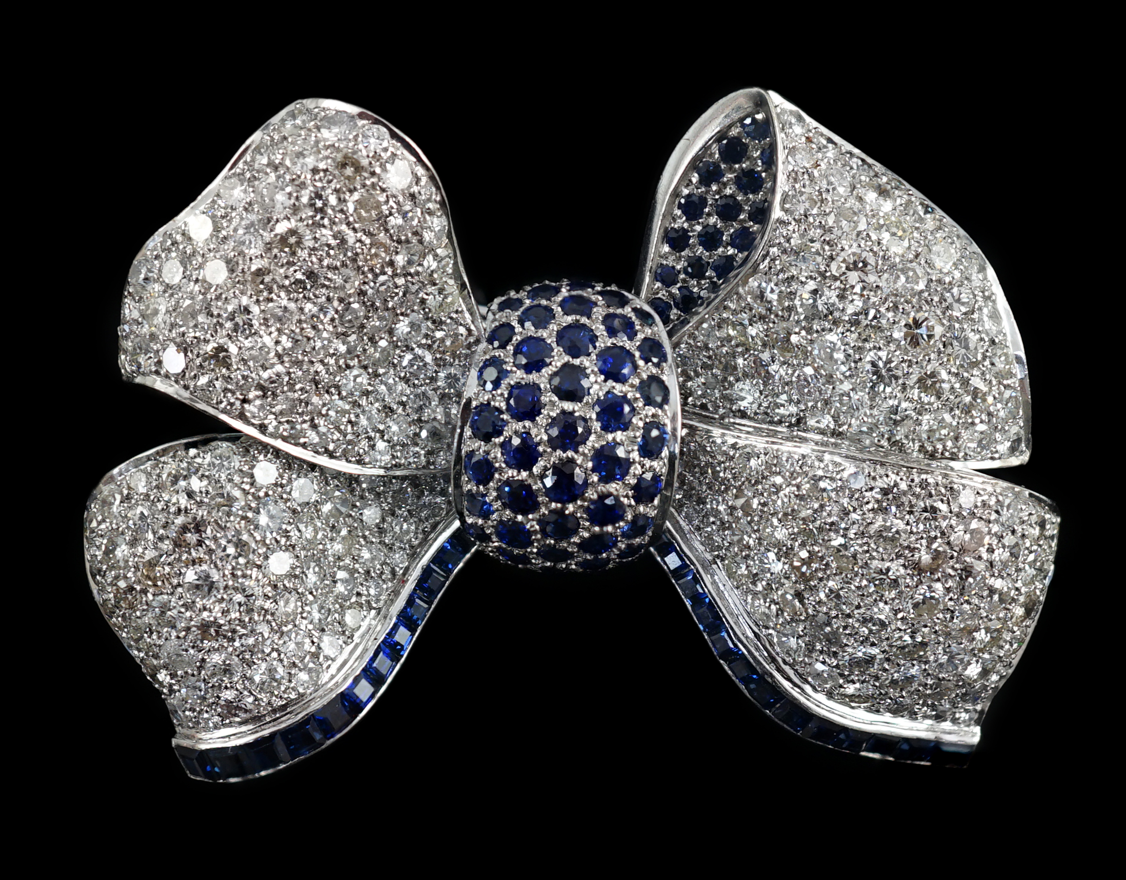 A modern white gold and pave set diamond and sapphire set ribbon bow brooch